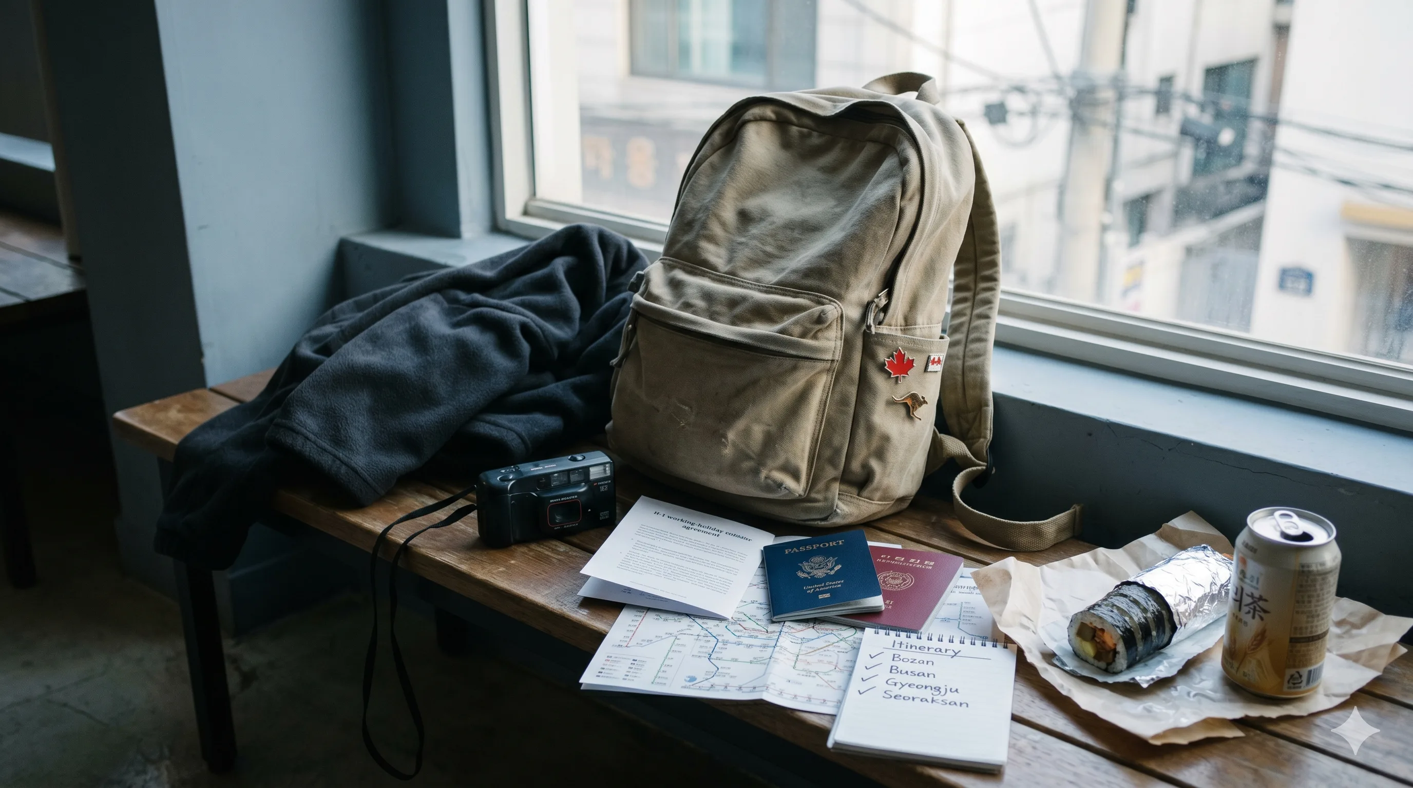 Worn canvas backpack on a hostel bench beside a folded fleece jacket and a film camera, two differently colored passports fanned beside an open H-1 working-holiday agreement leaflet, a printed Seoul subway map and handwritten itinerary, enamel pins of a maple leaf and a kangaroo, a half-eaten kimbap and a can of barley tea, late-afternoon light through a Hongdae hostel window — Korea H-1 working holiday visa hub by nationality